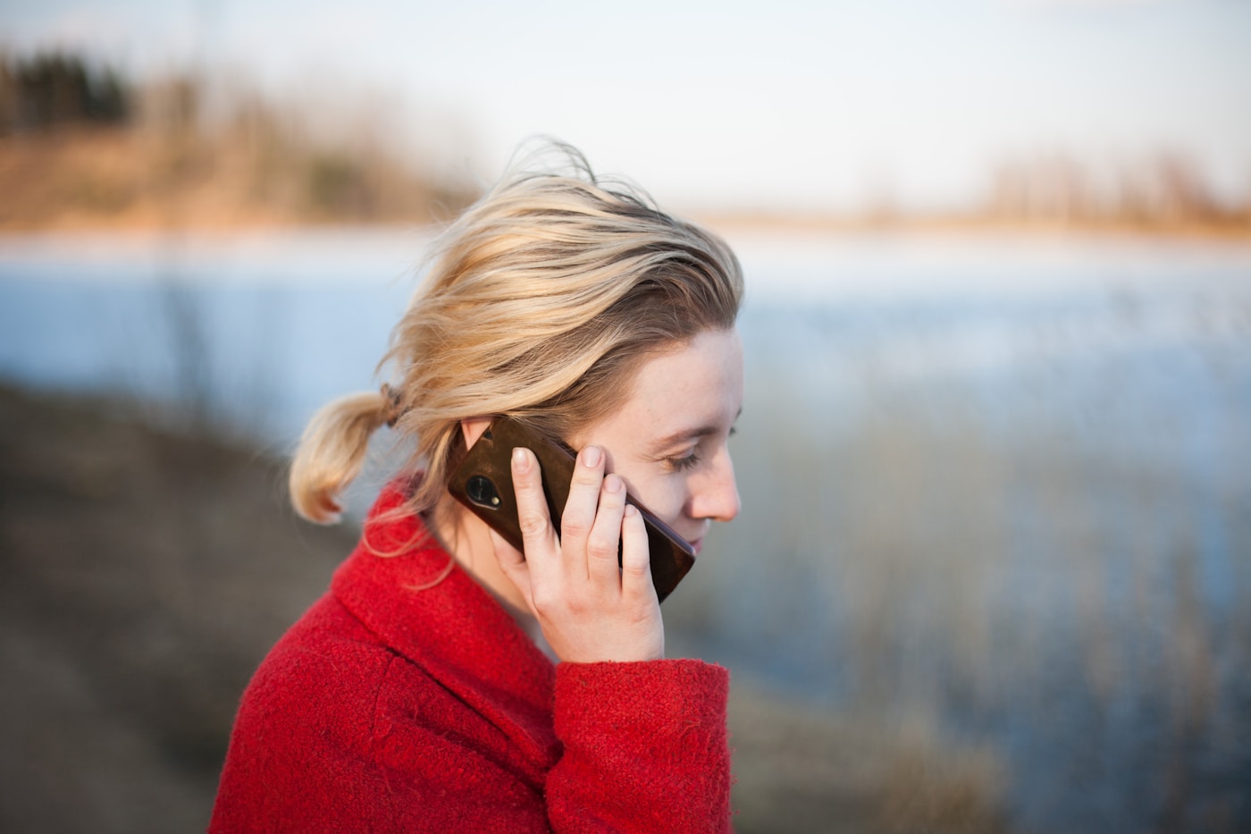 A person taking a phone call outdoors, looking cautious